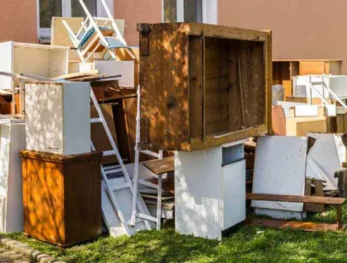 Ausgeräumte Möbel und Küchenteile vor einem Haus, bereit zur Abholung